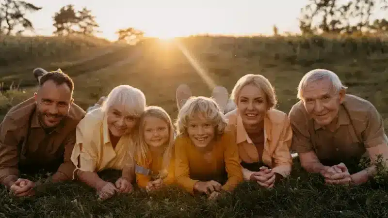 A group of six people lies on the grass, enjoying a golden sunset in a serene outdoor setting A group of six people lies on the grass, enjoying a golden sunset in a serene outdoor setting